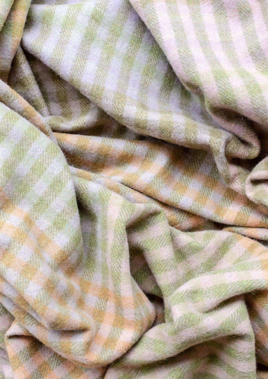 A gingham check print throw in mix of pastel and earthy greens and browns.