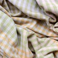 2: A gingham check print throw in mix of pastel and earthy greens and browns.