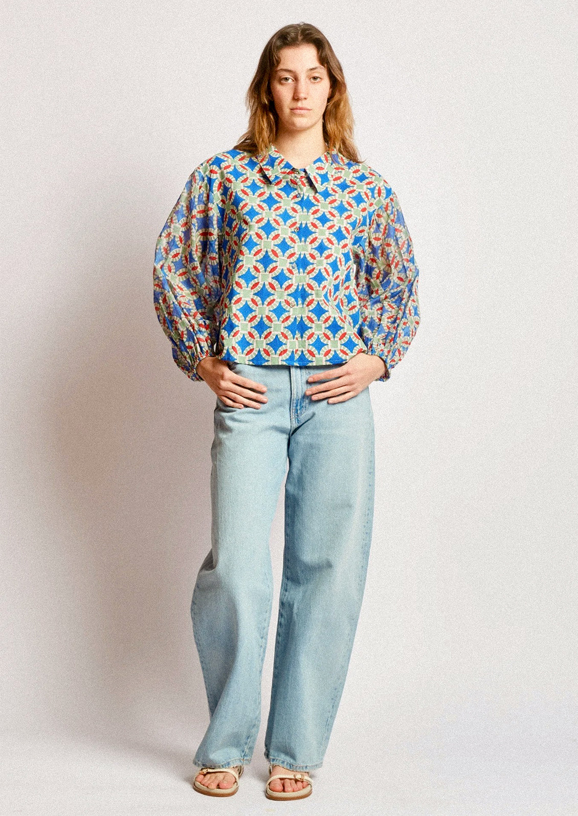 A woman wearing a shirt in blue, red and green geometric block print.