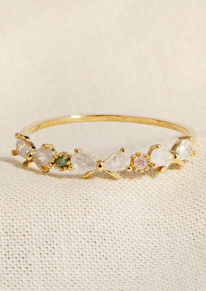 A gold ring with clear crystal bows and pink and green round stones in between.