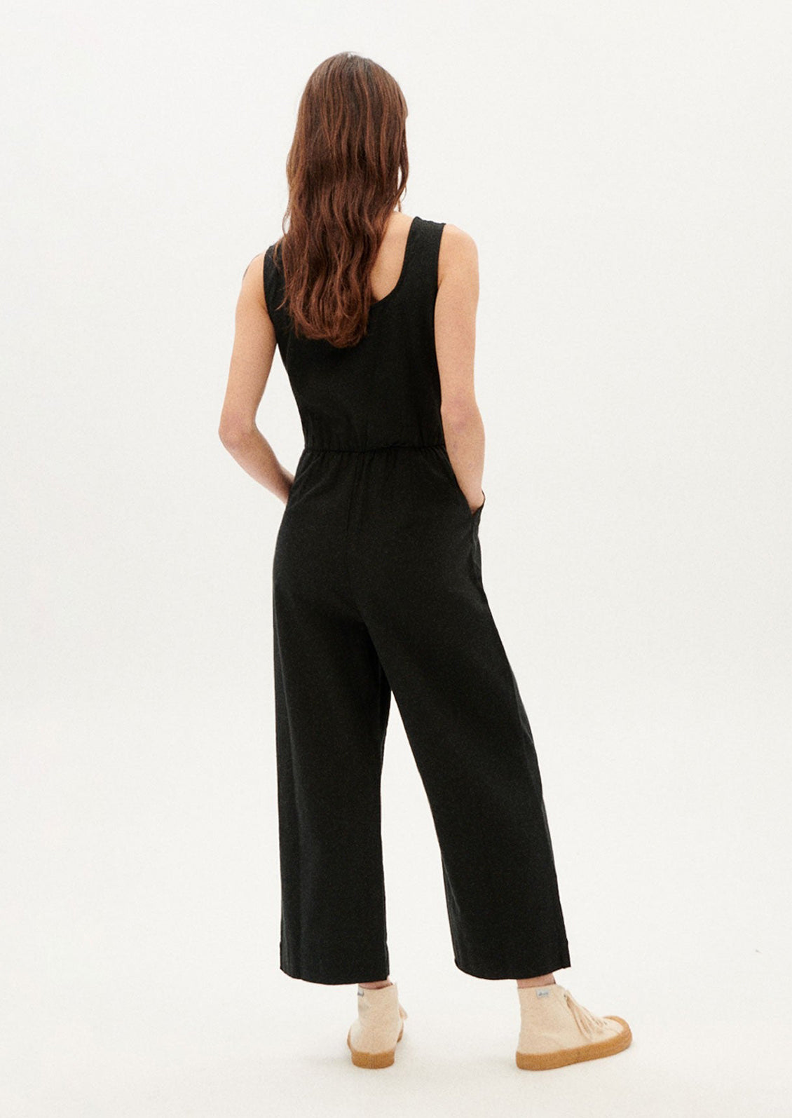 A woman wearing a black one piece jumpsuit with scoop neck.