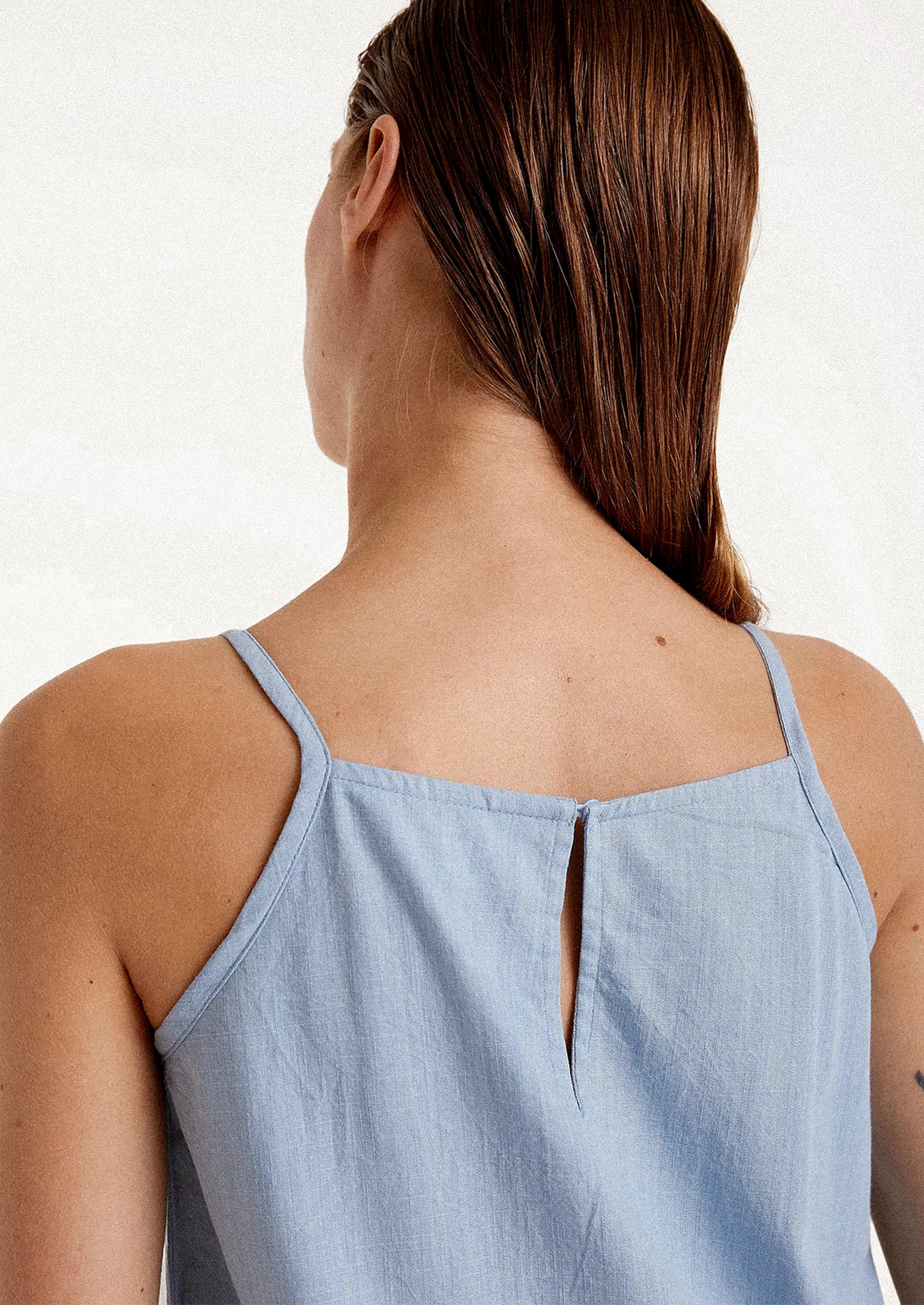 A woman wearing a knee-length dress in blue chambray cotton.