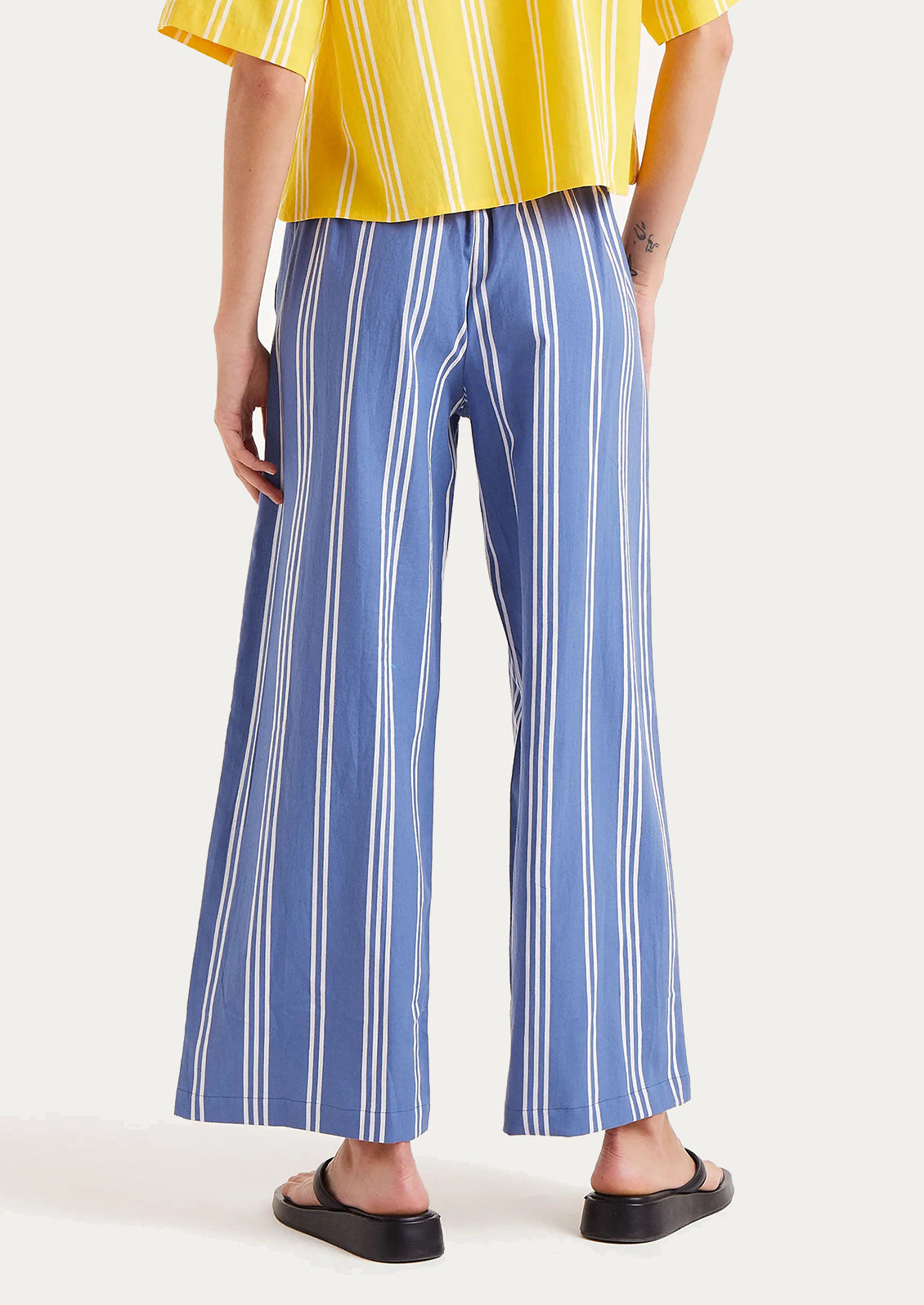 A woman wearing a pair of blue straight leg pants with vertical white stripes.