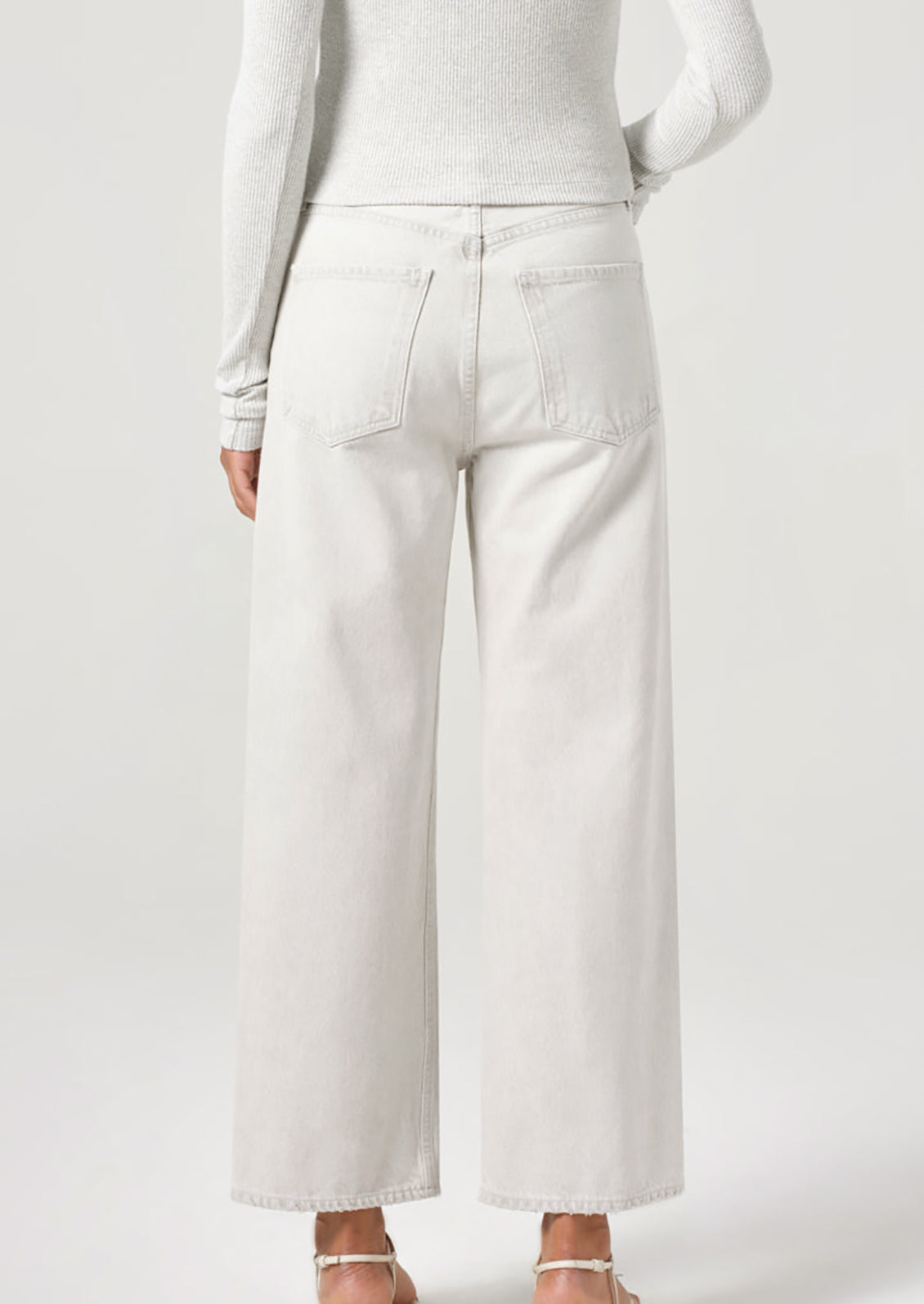 A person wearing a pair of wide leg jeans in light white-grey wash.