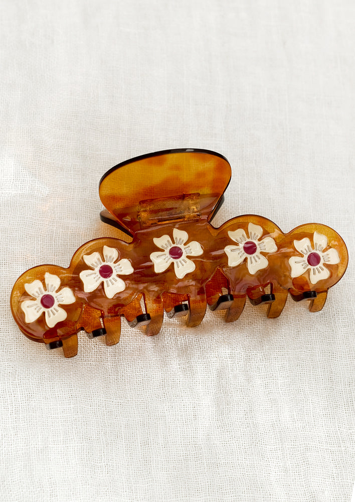 A brown translucent hair claw with white and red flowers.