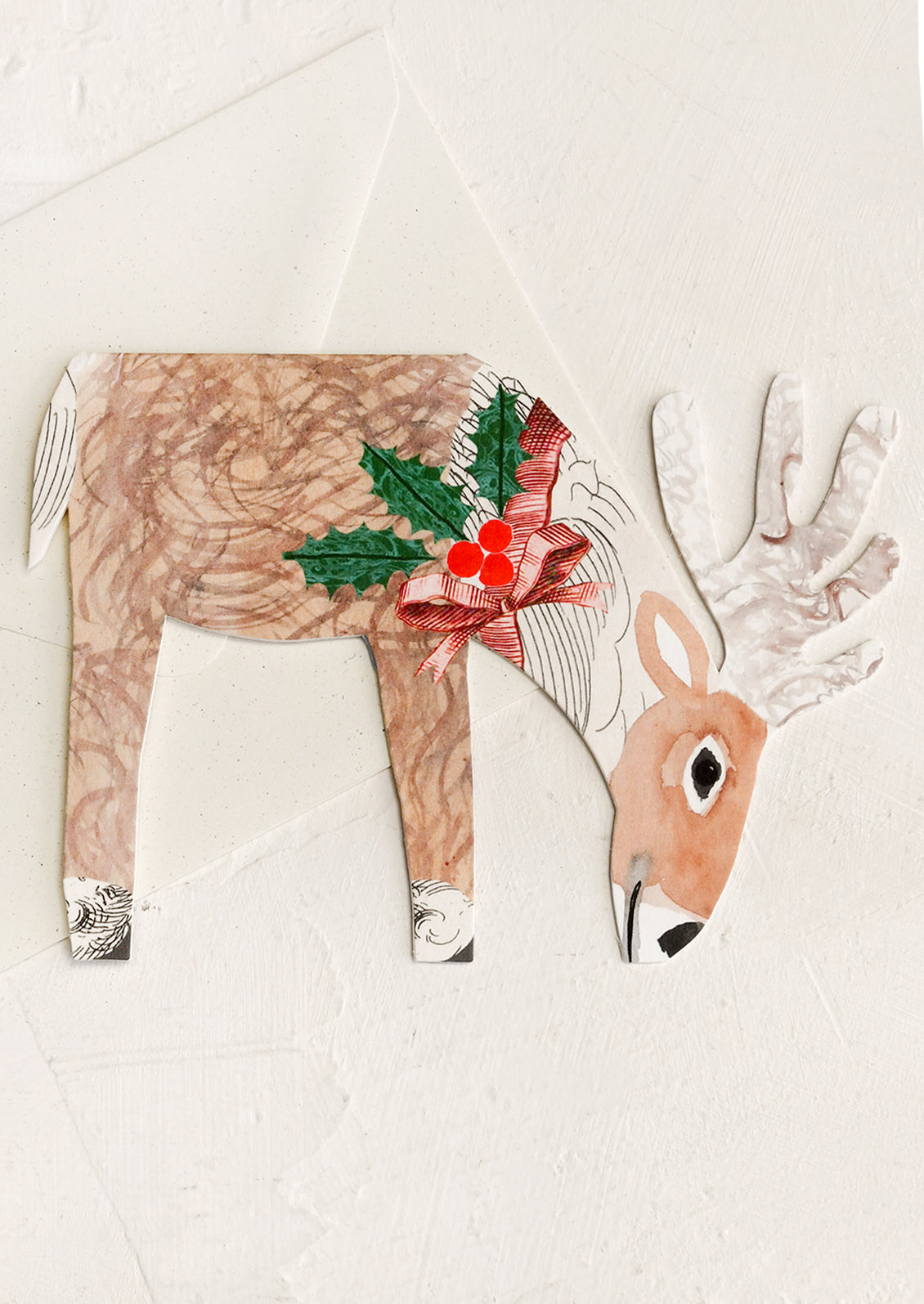 A greeting card in diecut shape depicting a reindeer wearing a holly necklace.