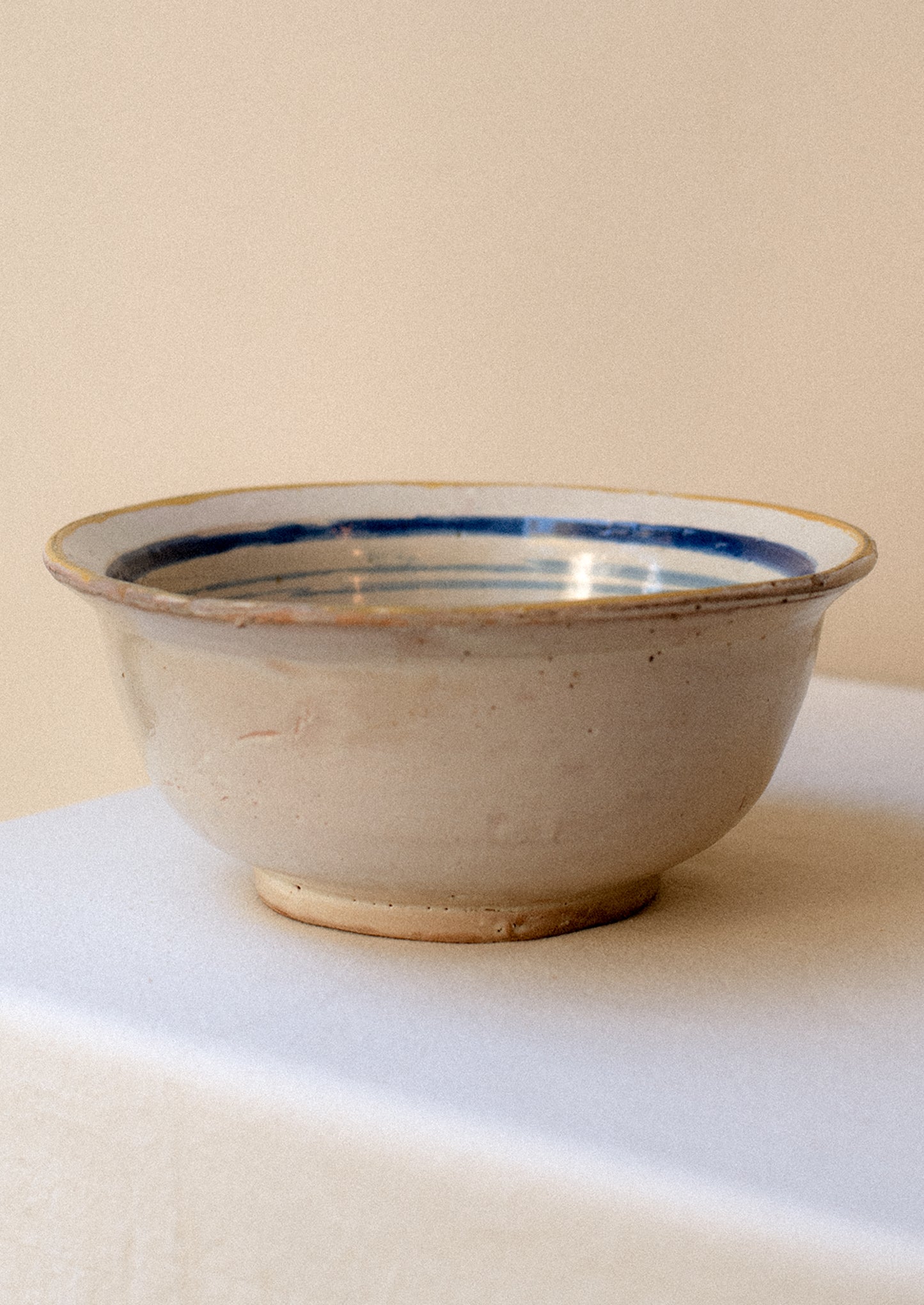 An antique ceramic serving bowl with painted blue rim and pink floral pattern.