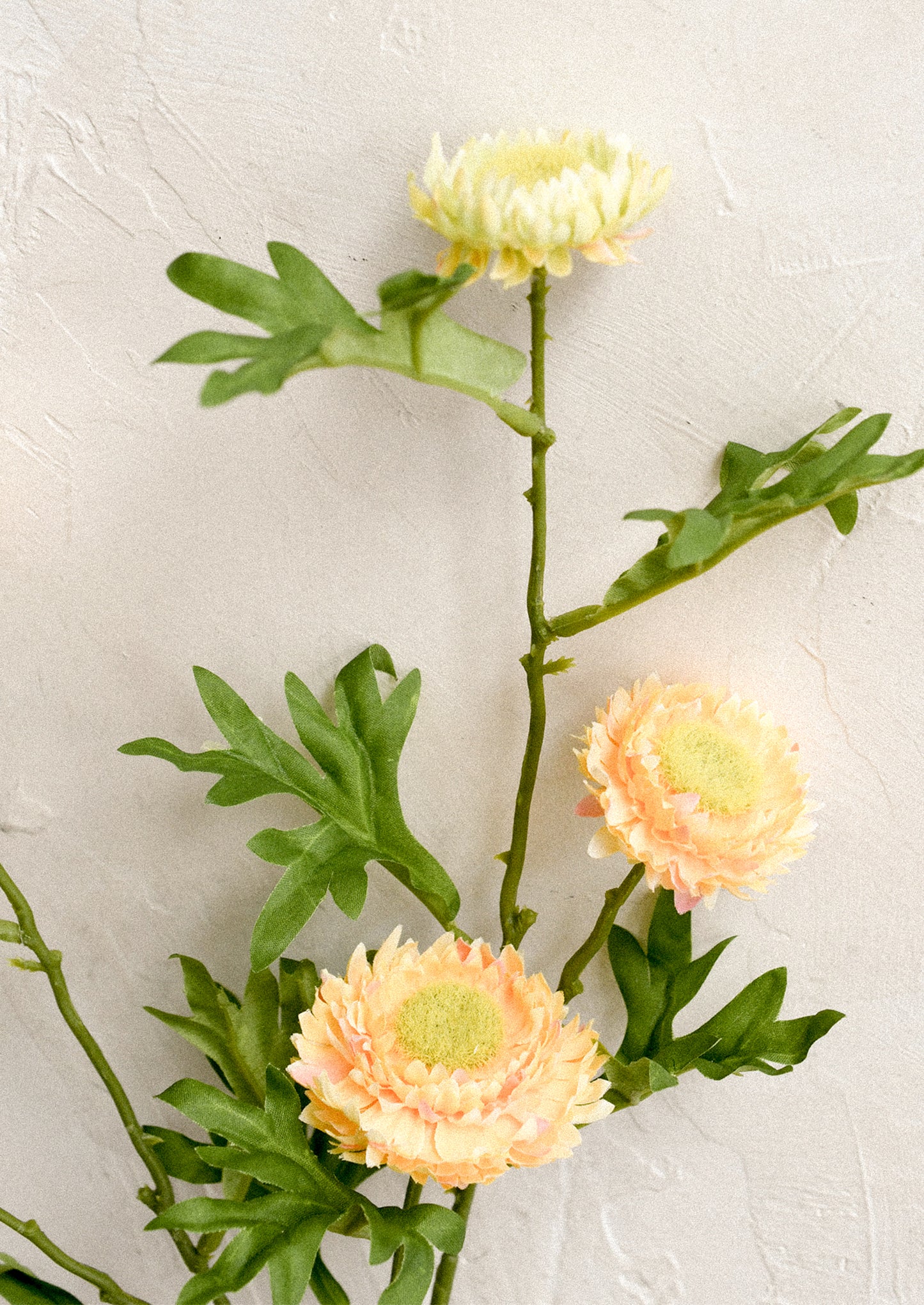 A faux floral spray depicting orange strawflower.