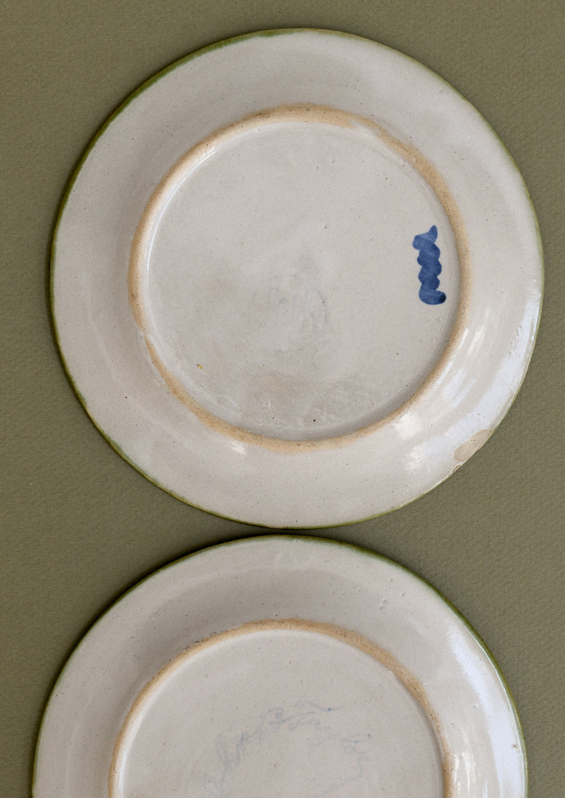 A pair of floral and squiggle painted plates in green, blue and orange.