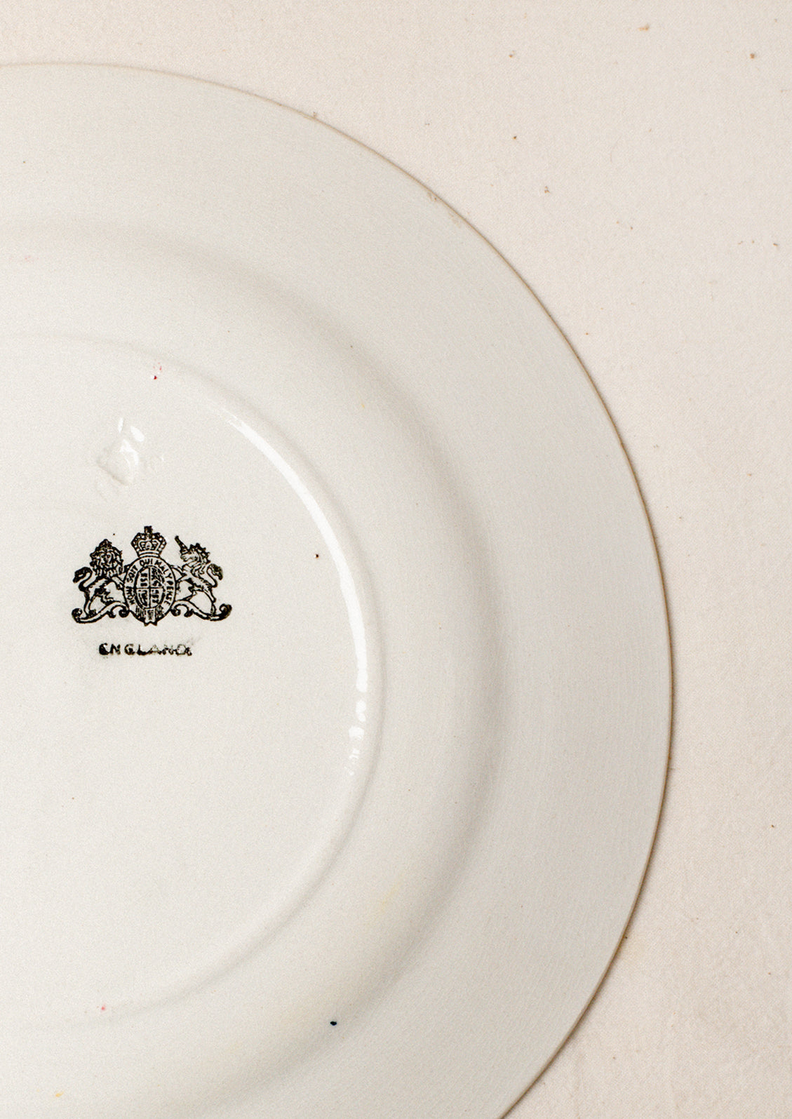 A pair of white plates with blue and red floral pattern around rim.