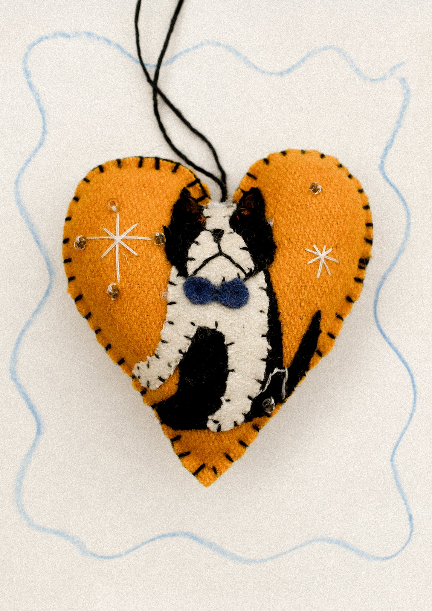 Heart-shaped ornament with a black and white dog design on an orange background