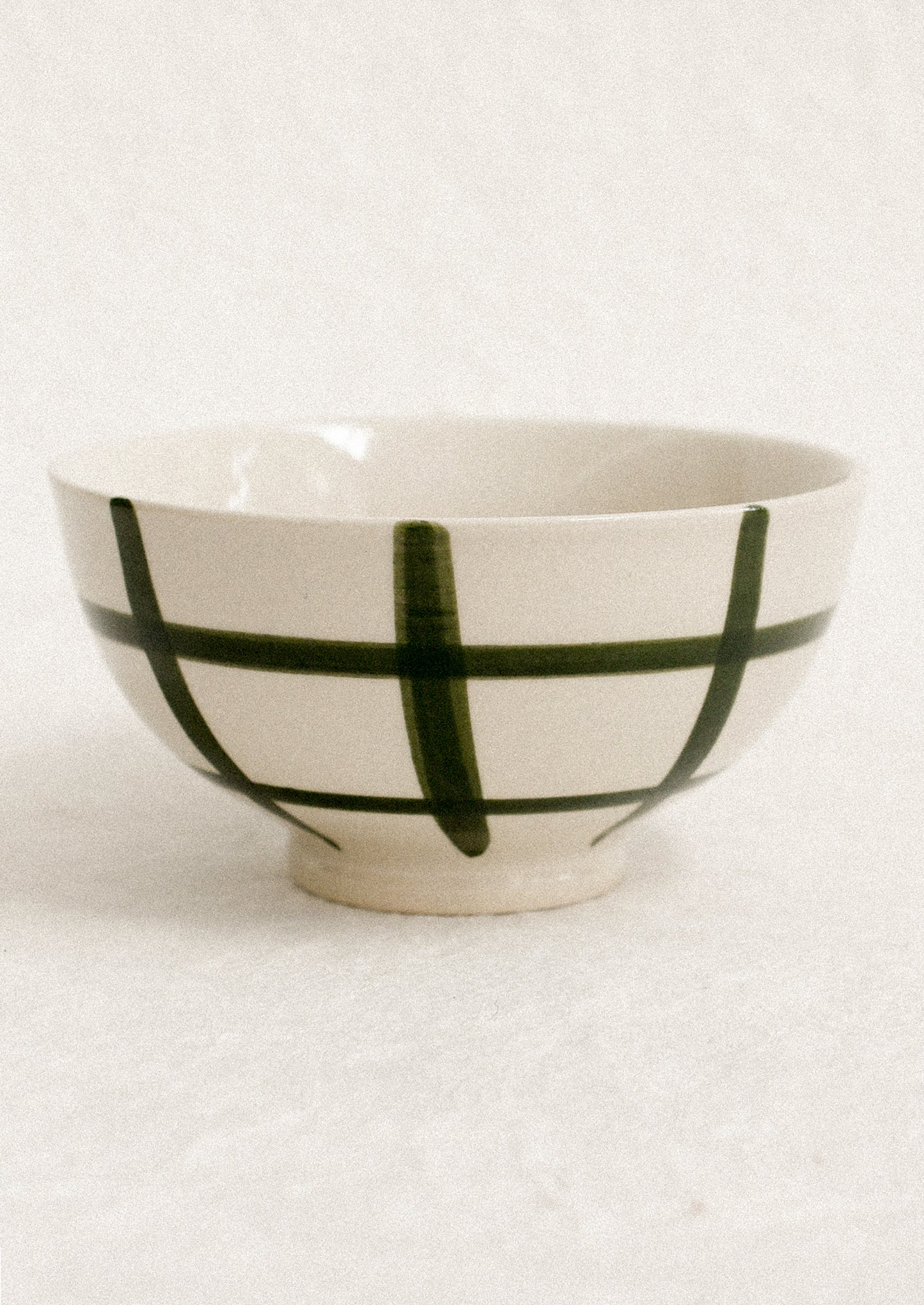 A small white porcelain bowl with painted grid pattern.