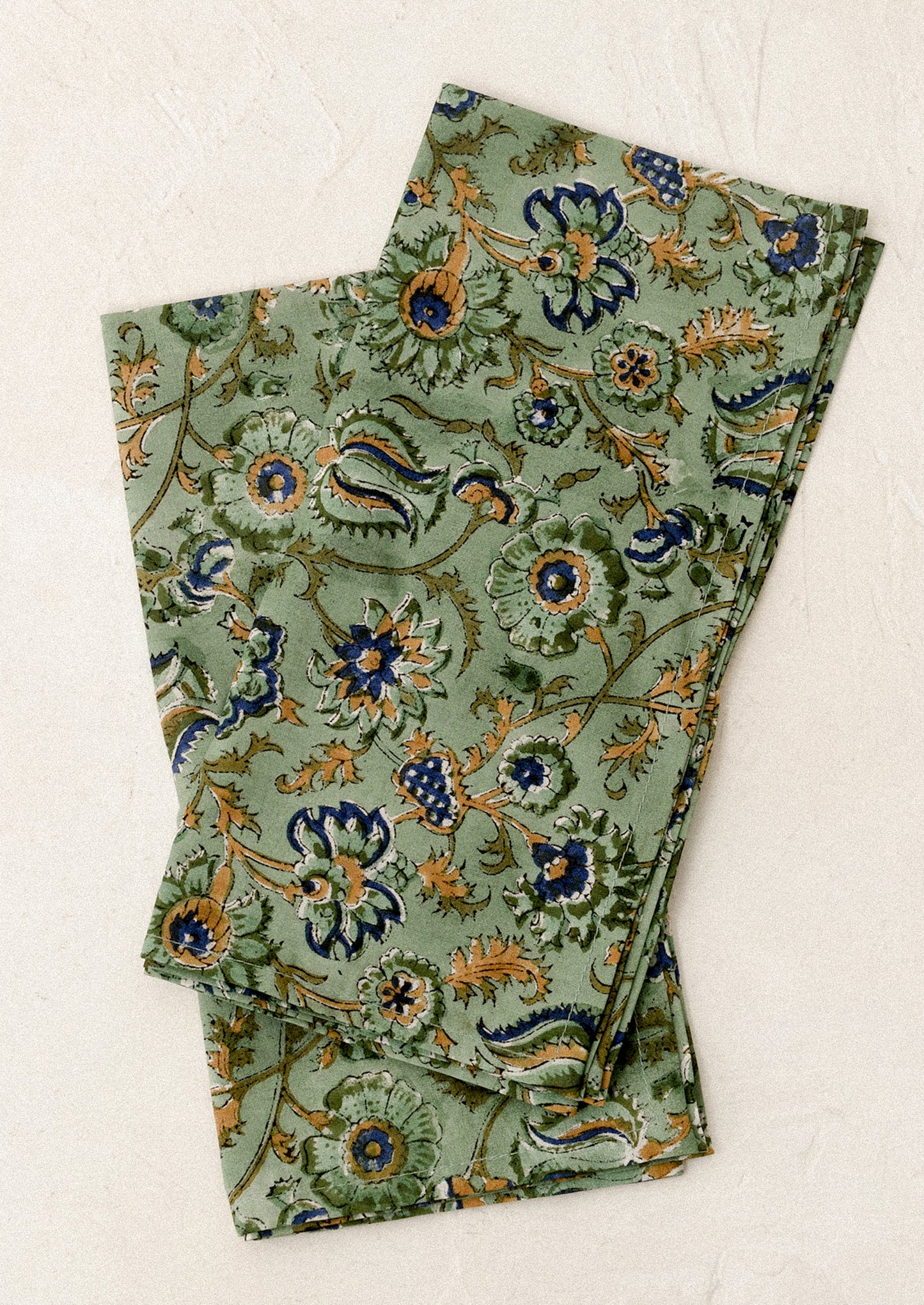 Folded green napkins with floral pattern on a white background