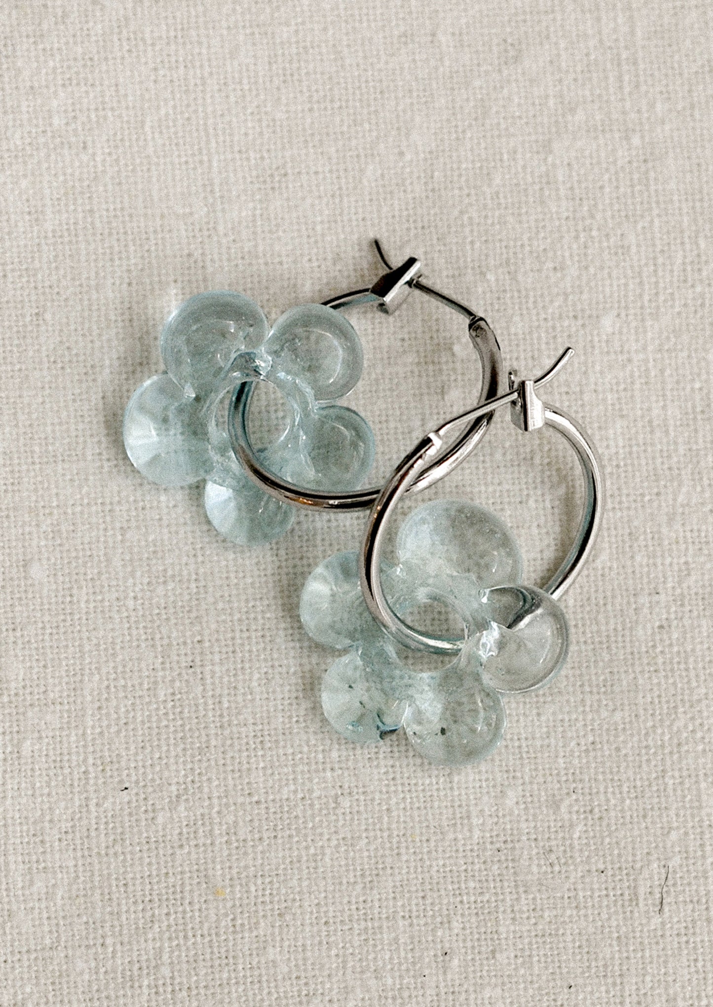 A pair of silver hoop earrings with floral Murano glass accents, displayed against a white background.