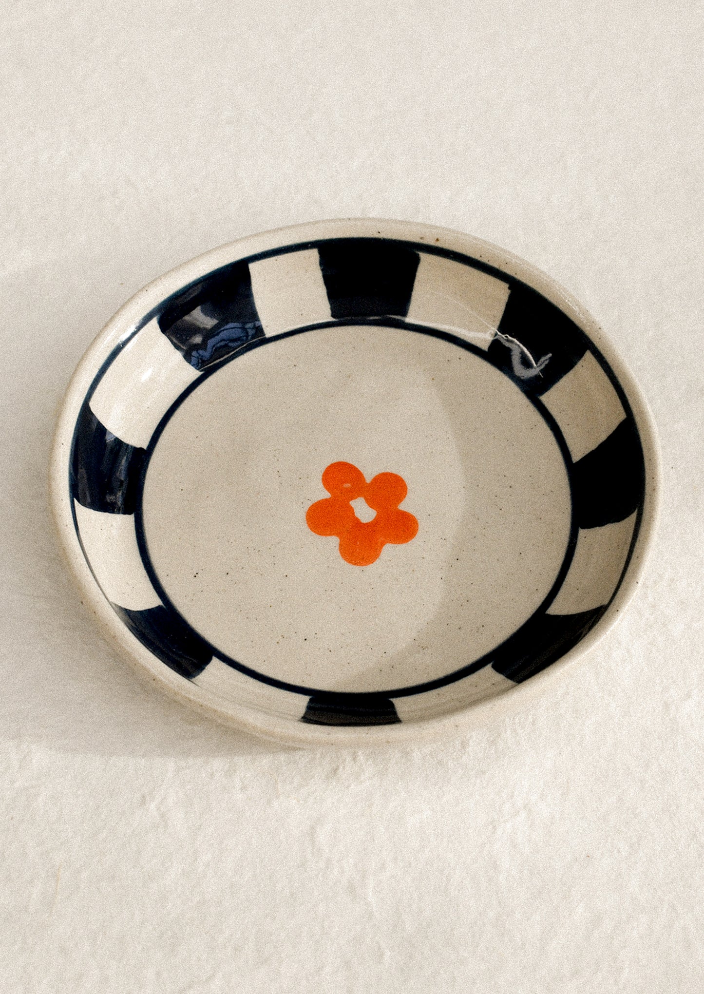 A small ceramic dish with raised sides with hand painted flower motif.