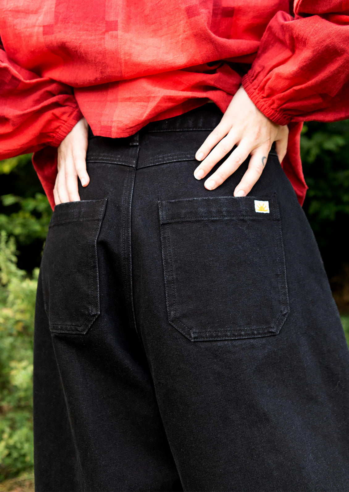 A woman wearing a pair of pleat front, balloon leg jeans in dark grey color.