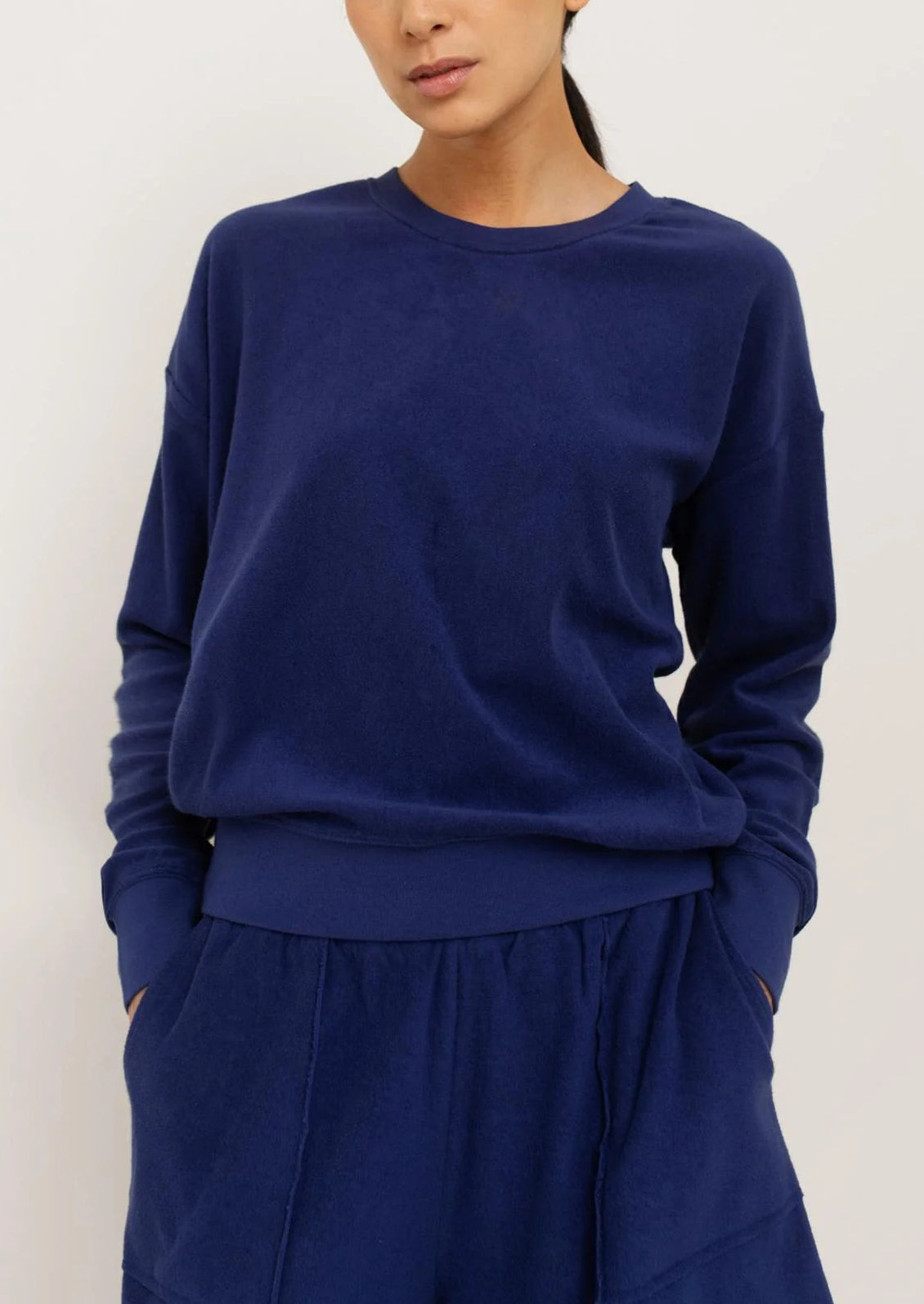 A woman wearing a crewneck sweatshirt in terry cloth fabric in navy blue.