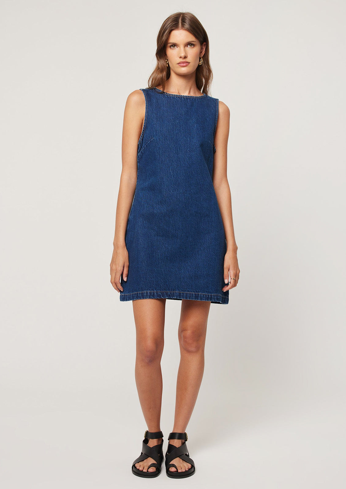 A woman wearing a short shift dress in dark blue denim.