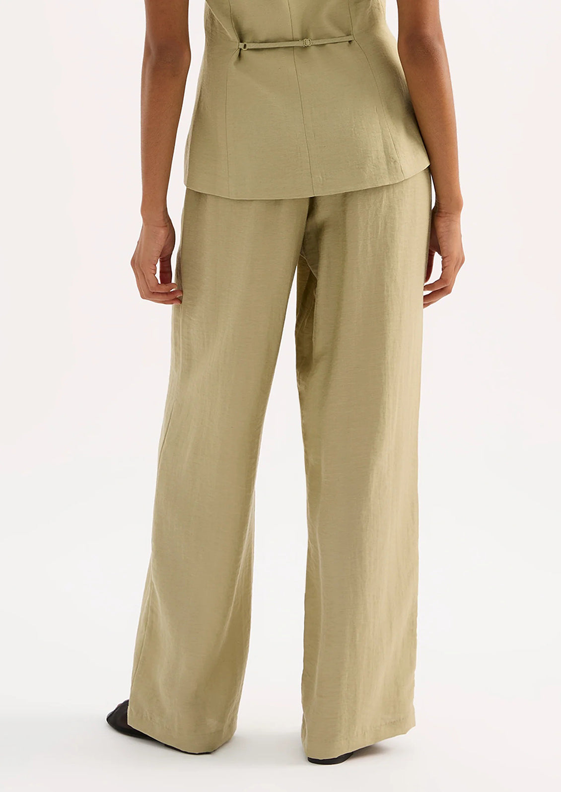 A woman wearing a pair of green suiting pants.