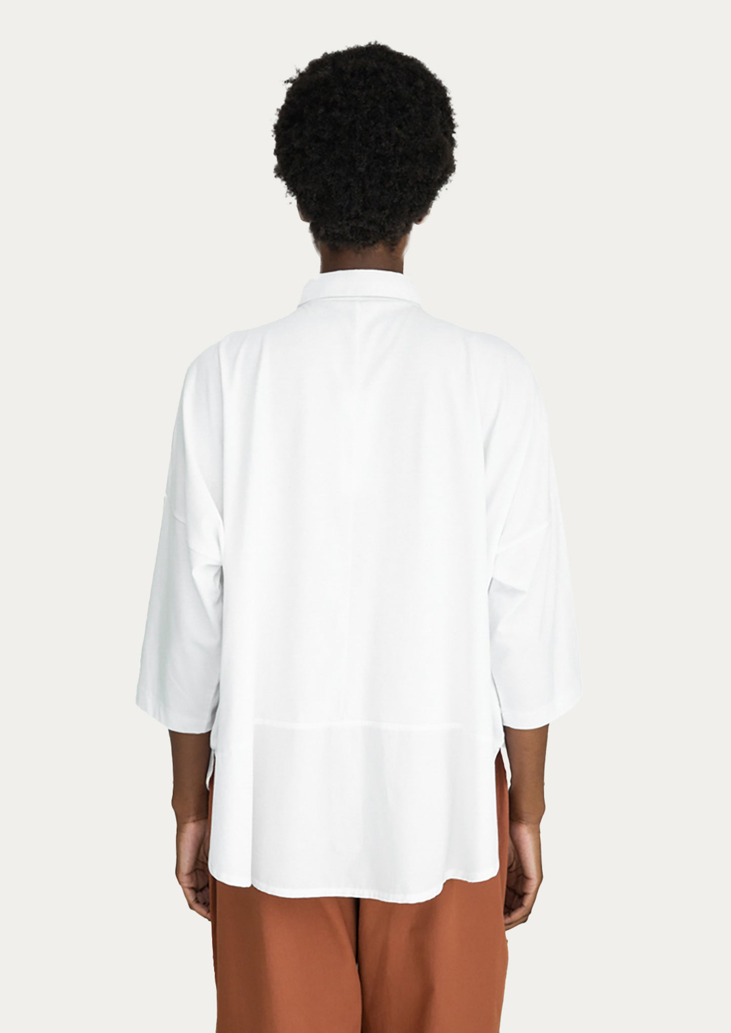 A woman wearing a blousy white cotton shirt.