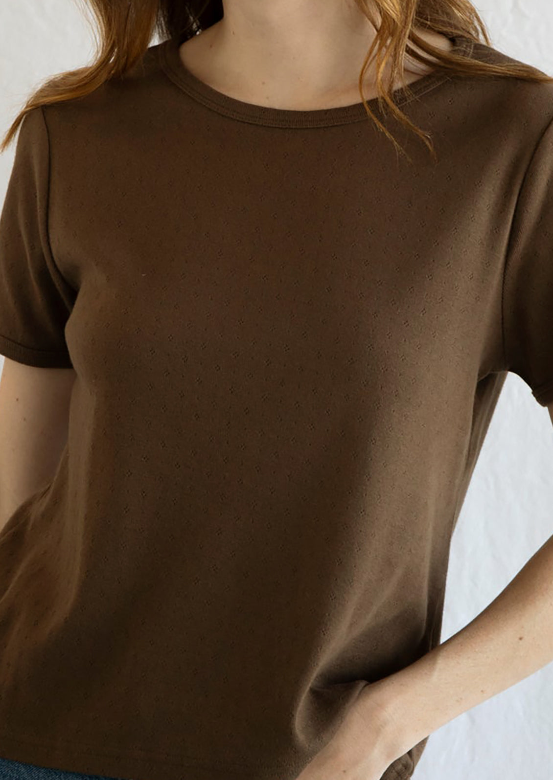 A woman wearing a pointelle stitch t-shirt in chocolate brown color.