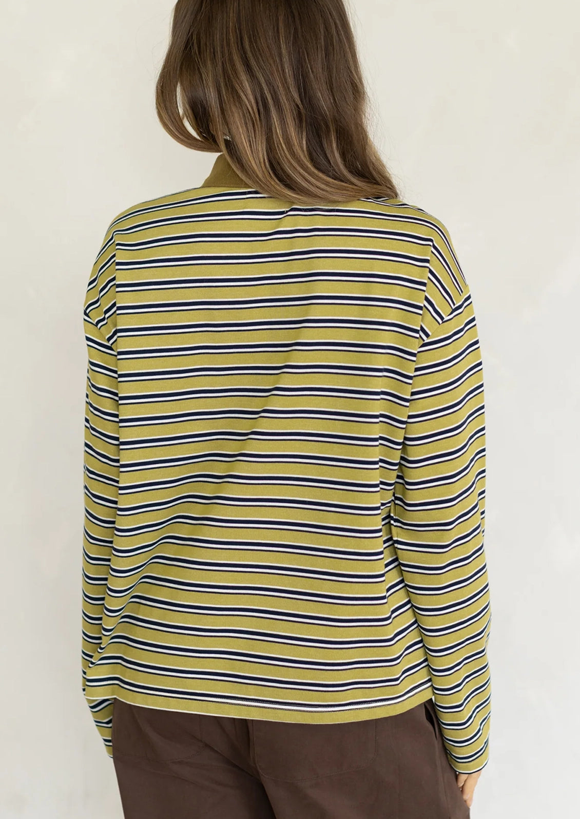 A woman wearing a long sleeve striped t-shirt with polo collar, chartreuse with white and black stripes.