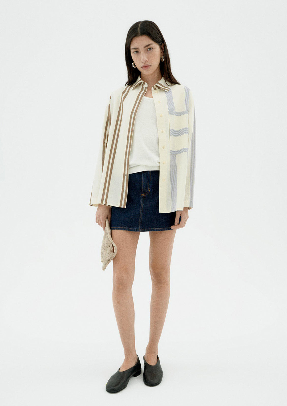 A woman wearing a button down collared shirt with half brown stripes, half blue stripes.