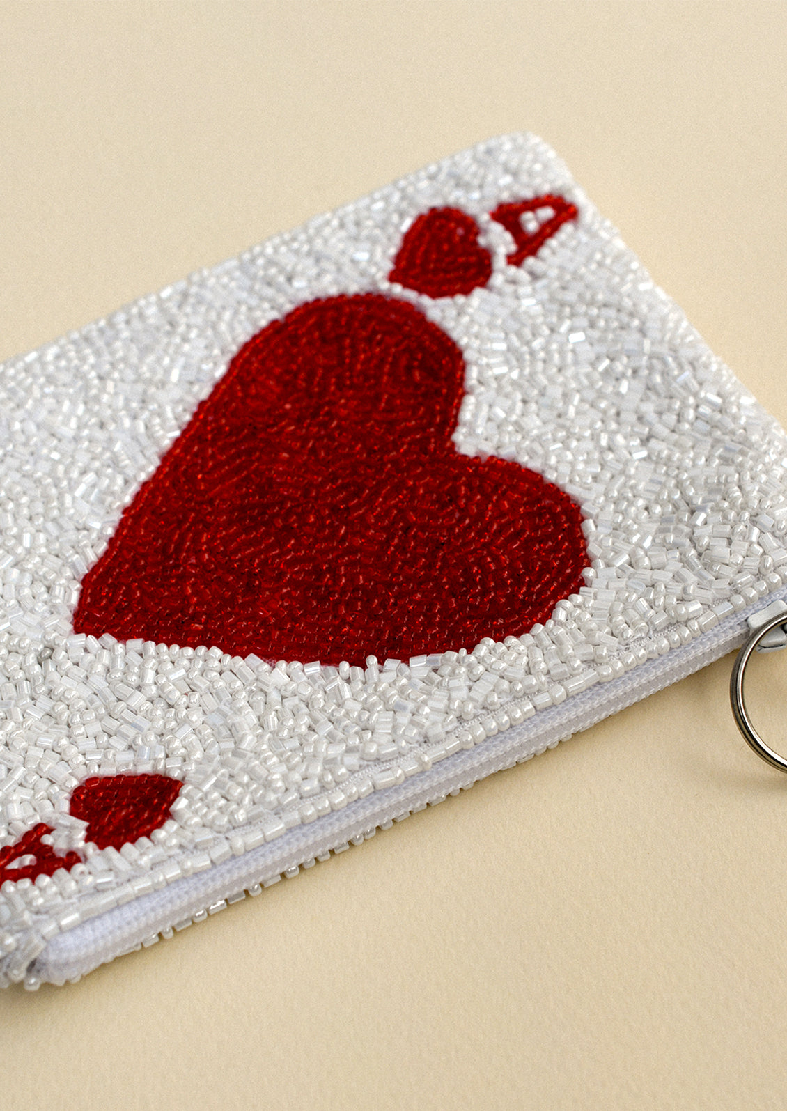 A white beaded coin pouch with ace of hearts design.