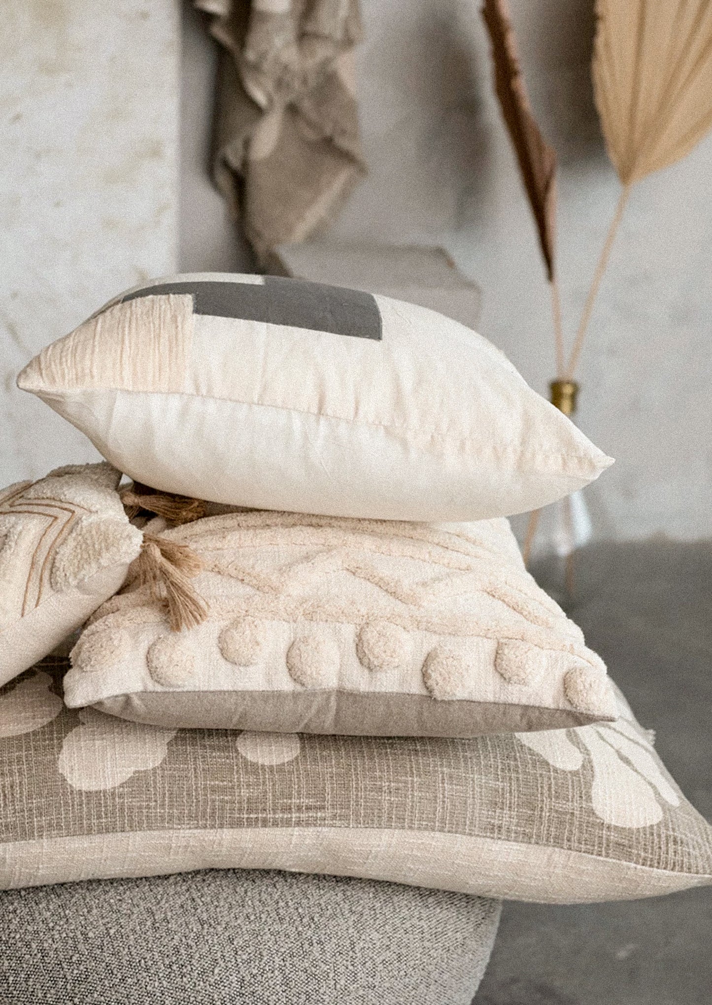 A throw pillow in sheer linen material with patchwork design in neutral colors.