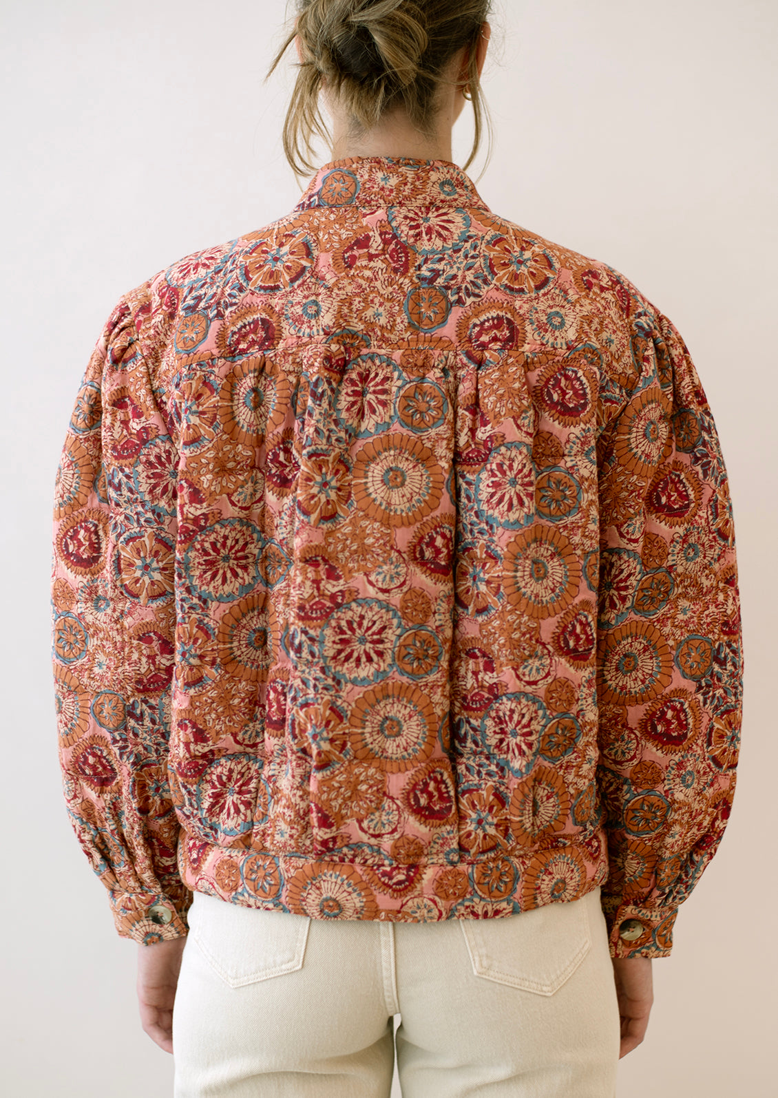 A woman wearing a cotton jacket in multicolor kaleidoscope print.