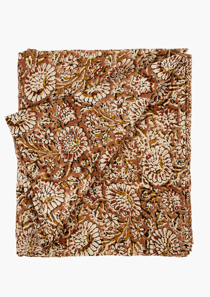 A block printed linen tablecloth/throw in rust, crimson and black floral print.