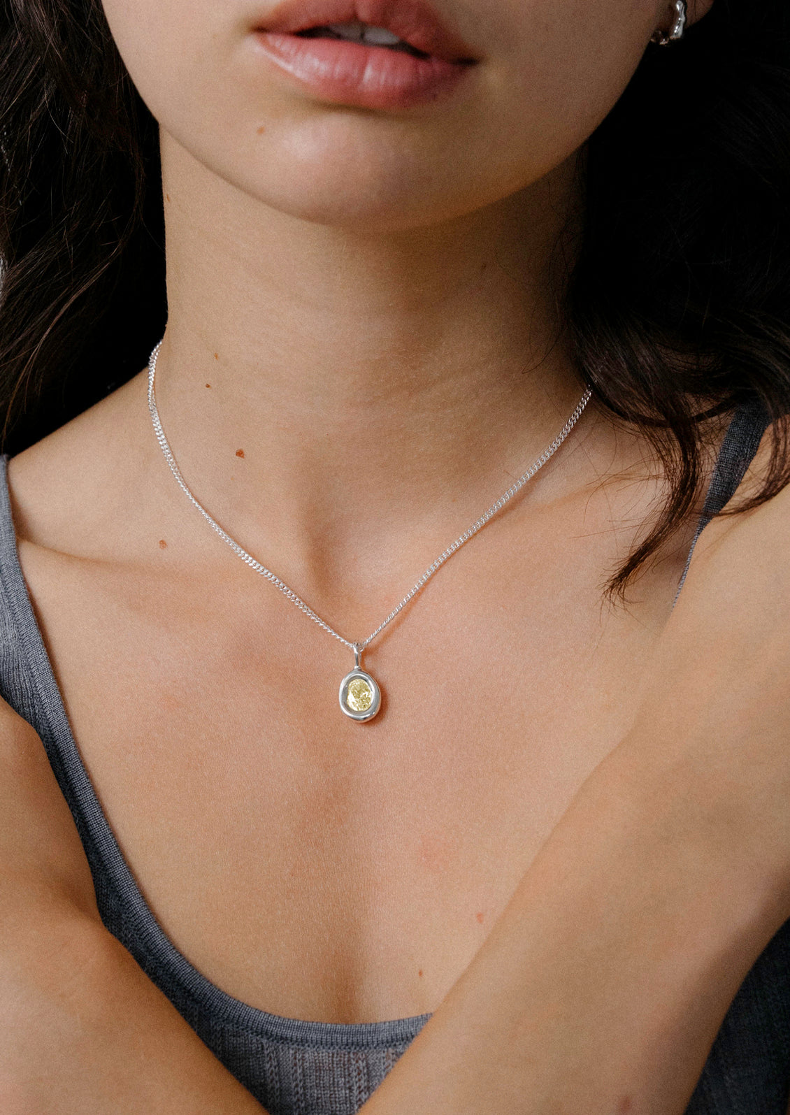 A woman wearing a sterling silver necklace with a yellow gemstone.
