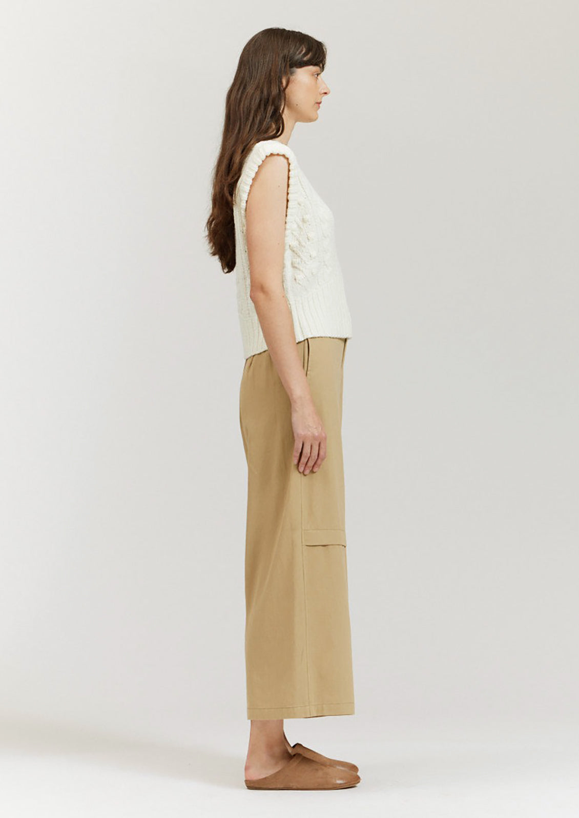 A pair of khaki colored wide leg pants with decorative knee pleat detail.