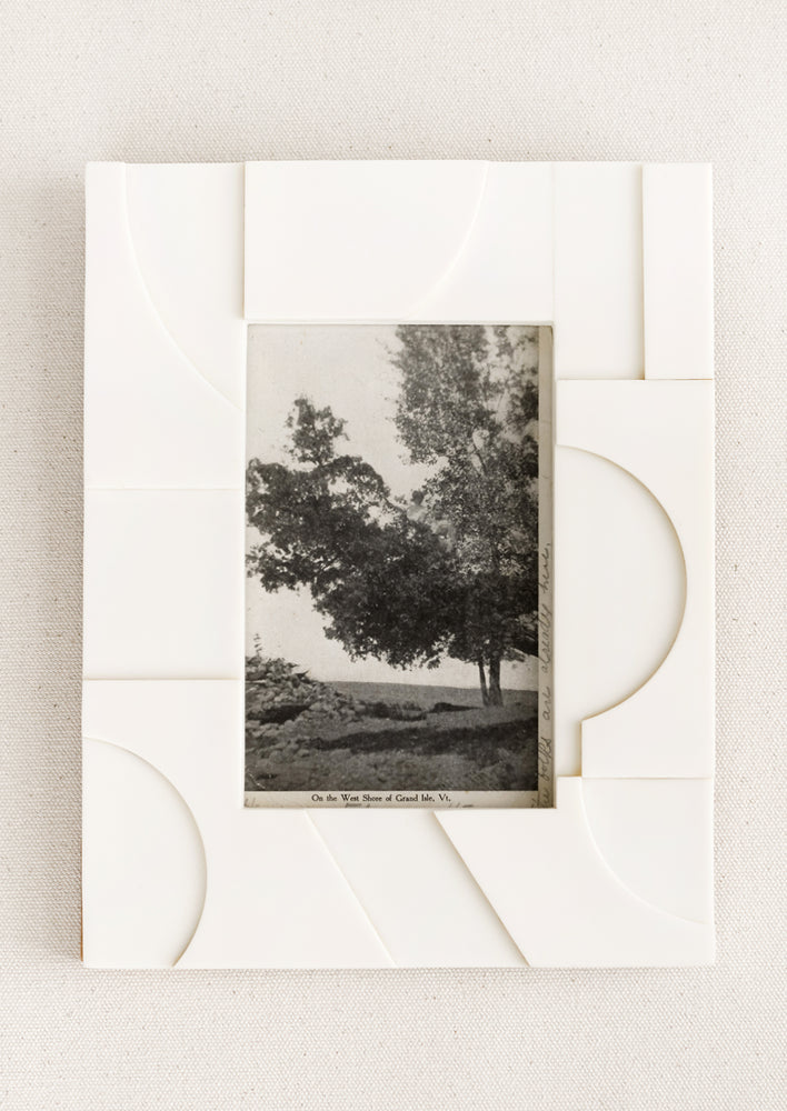1: An ivory resin frame with raised and depressed geometric shape pattern.