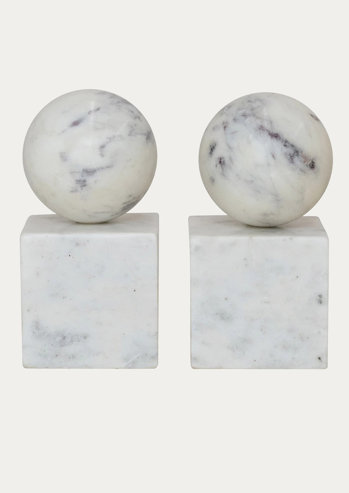 A pair of bookends in white marble with sphere on top of square base.