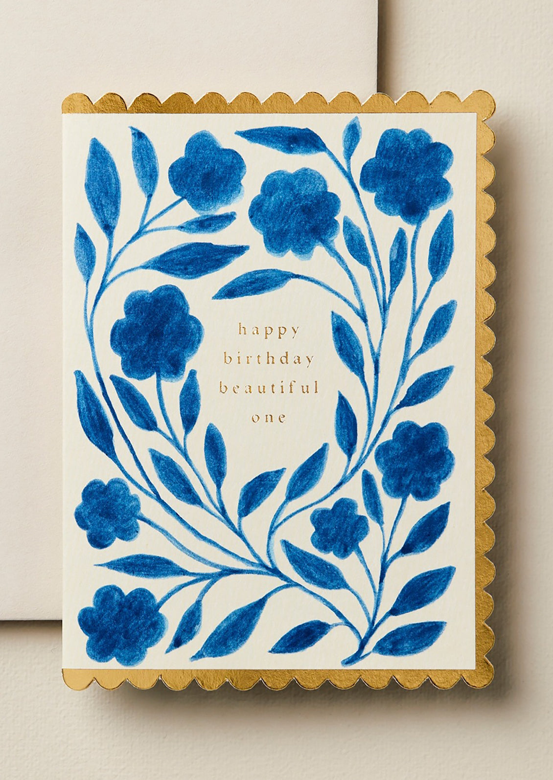 A blue floral print card with gold scalloped edges reading "Happy Birthday Beautiful One'.