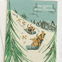 2: Greeting cards with illustration of dogs sledding down a hill, text reads "The Holidays Are Better Together".