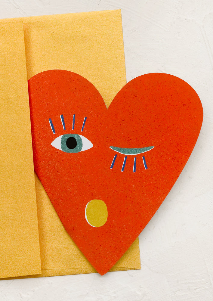 A heart shaped card, the heart has a face and is winking.