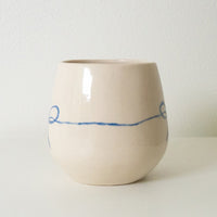 3: A white rounded ceramic cup with hand painted blue bow.