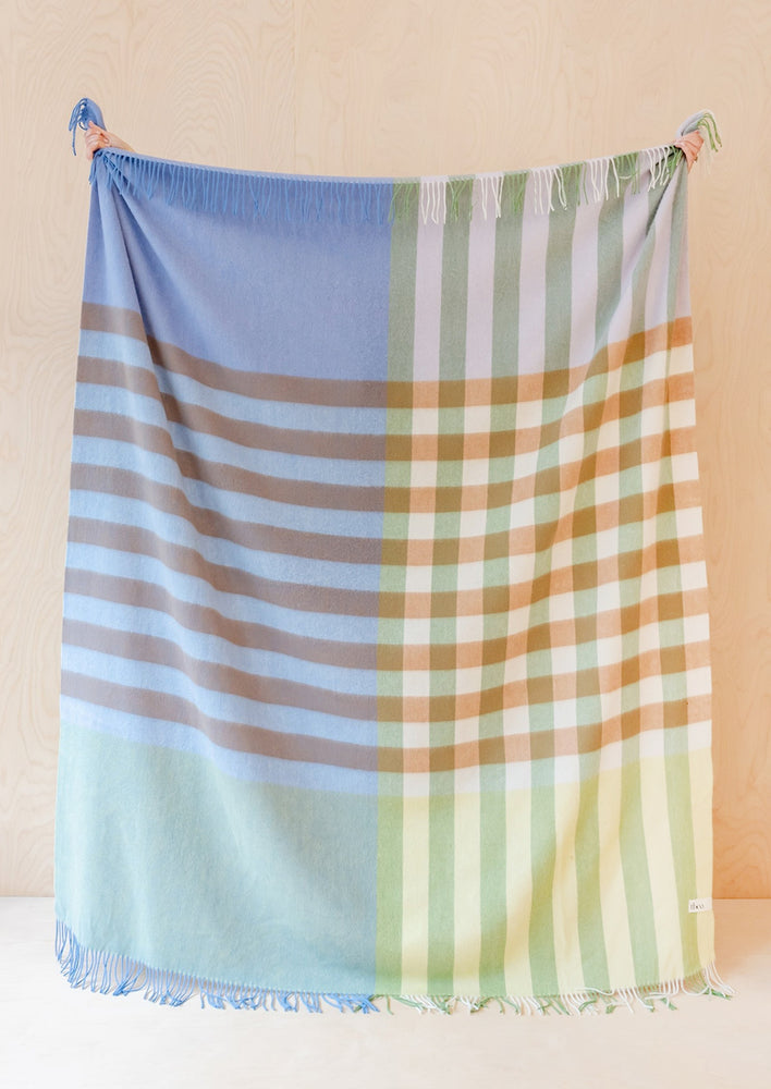 A lambswool blanket in stripe/check pattern, in shades of periwinkle, rust, aqua, brown and green.