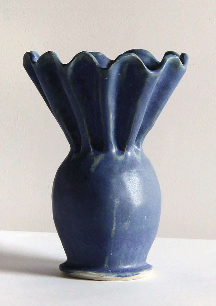 A blue handmade ceramic vase with wide pleated opening.