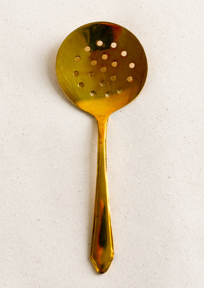A brass spoon with strainer holes.
