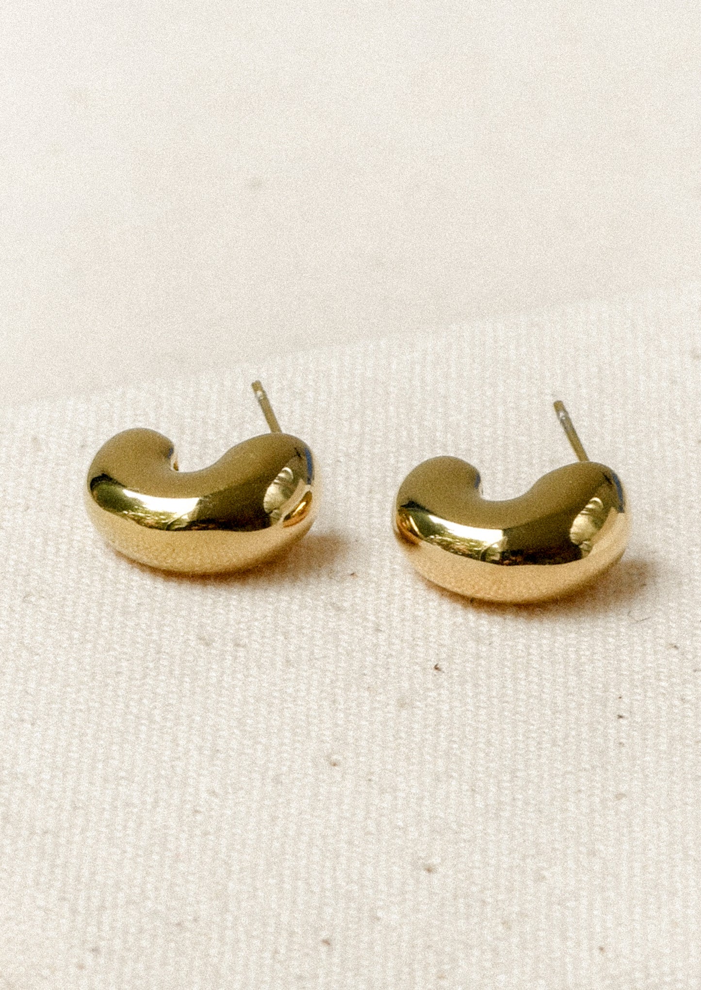 A pair of chunky gold half hoop earrings with post closures.
