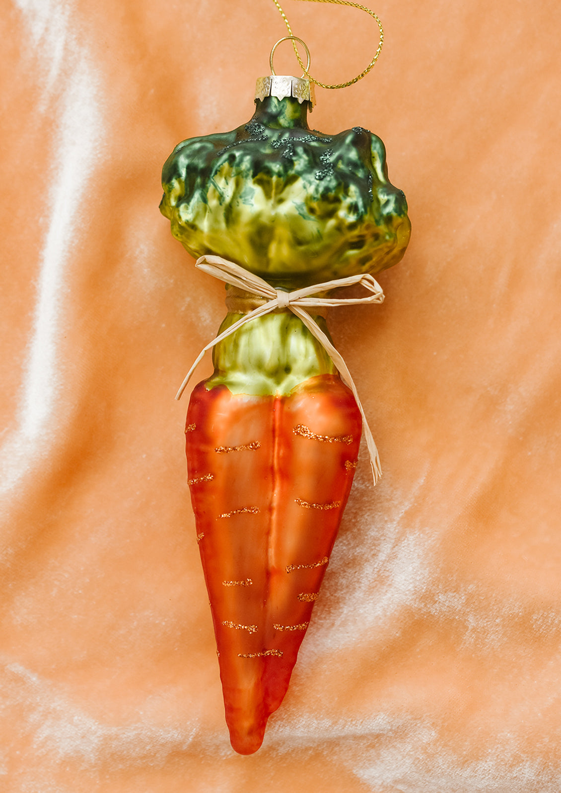 A glass ornament resembling a bunch of three carrots tied with a bow.