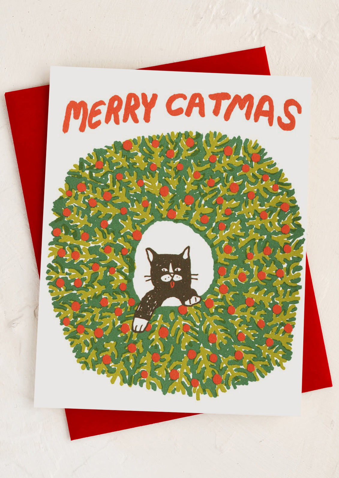 A card with illustration of cat in wreath, text reads "Merry Catmas".