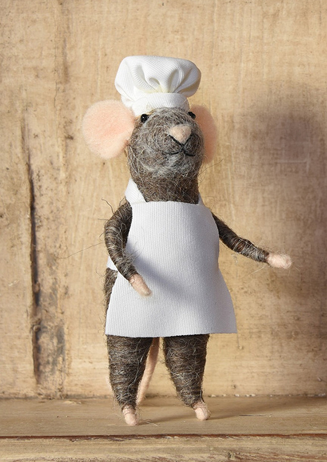A felted mouse ornament wearing a chef's hat and apron.