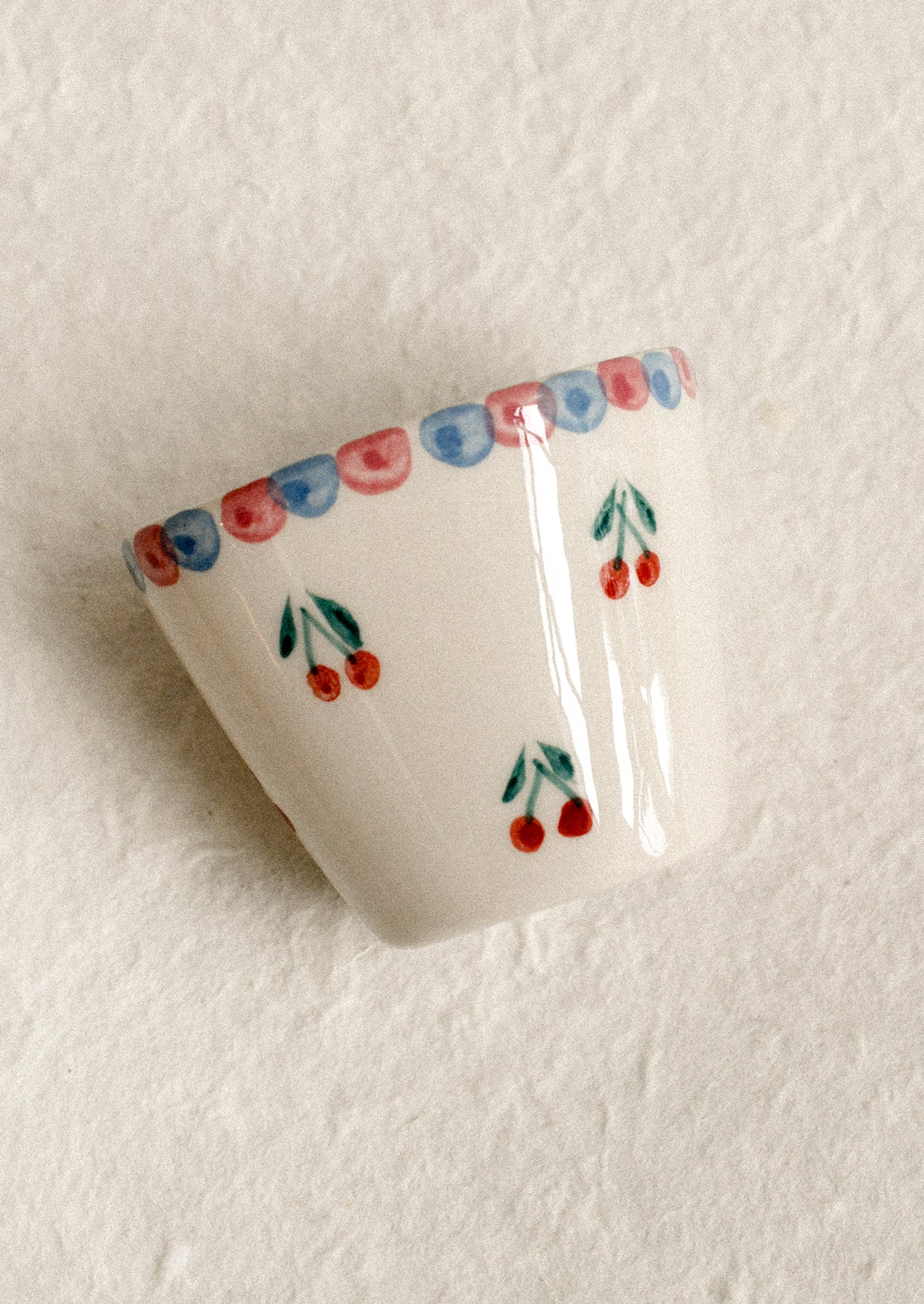 A small hand painted cup with cherry motif.
