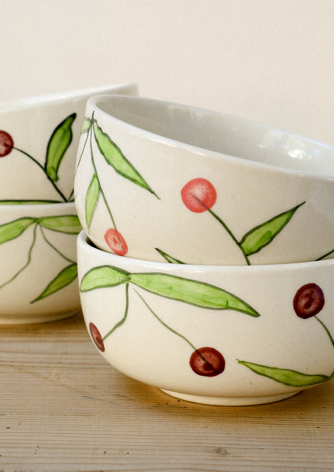 Stacks of ceramic bowls with a hand drawn illustration of cherries.