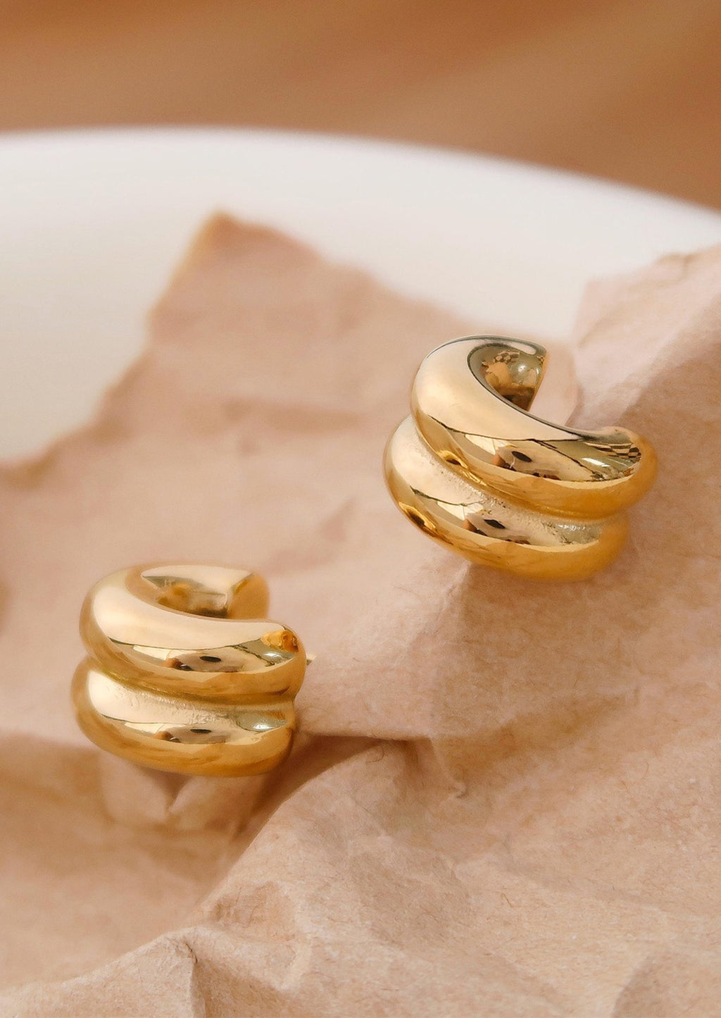 1: A pair of chunky rib textured hoop earrings in gold.