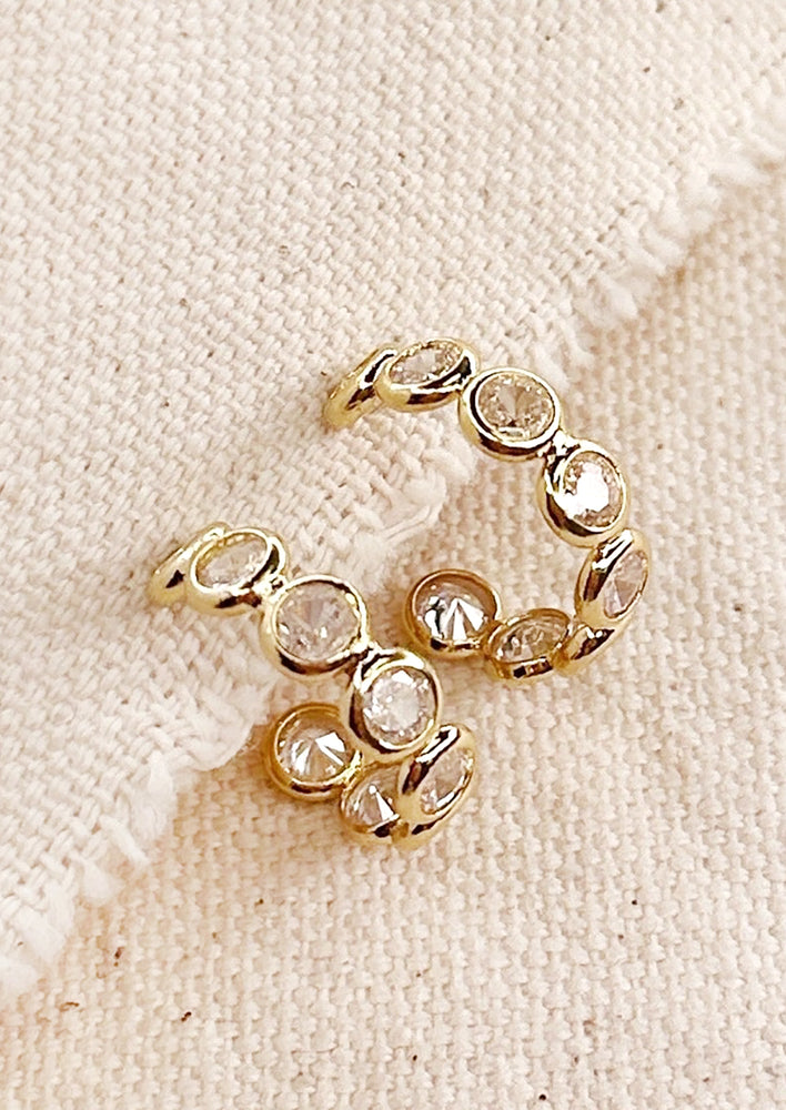 A pair of gold hoop earrings with clear bezeled circles.